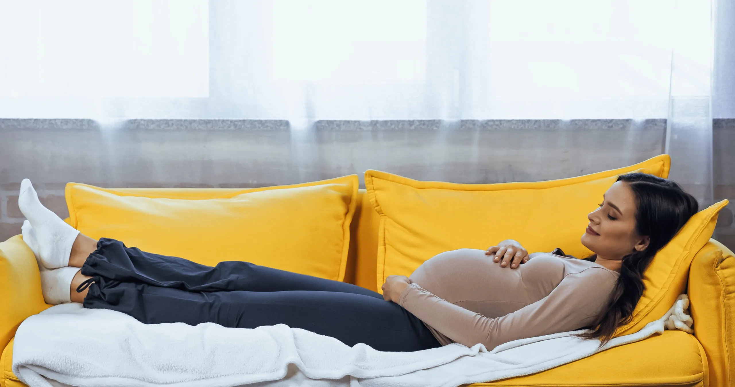 אישה בהריון שוכבת על הספה